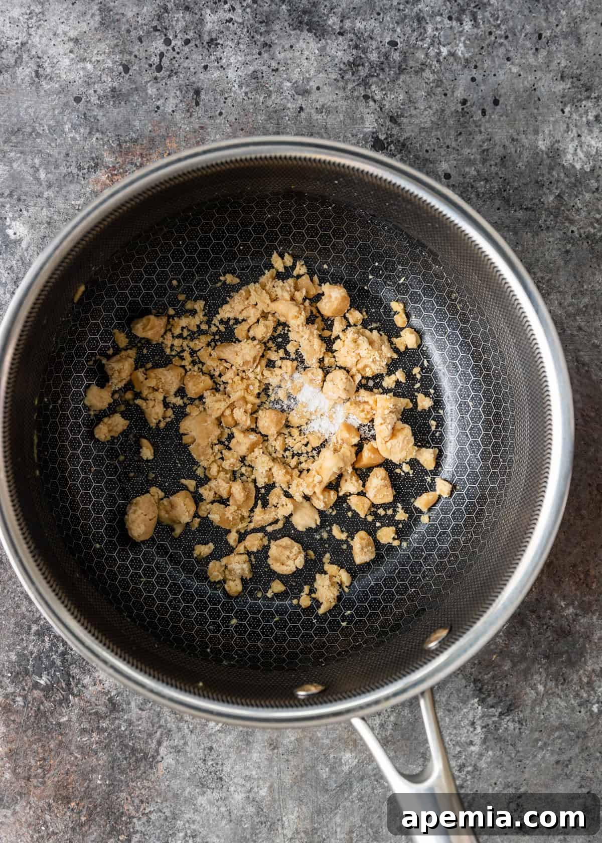 Overhead process shot: palm sugar and a pinch of salt are melted in a skillet, forming the base for the coconut sauce.