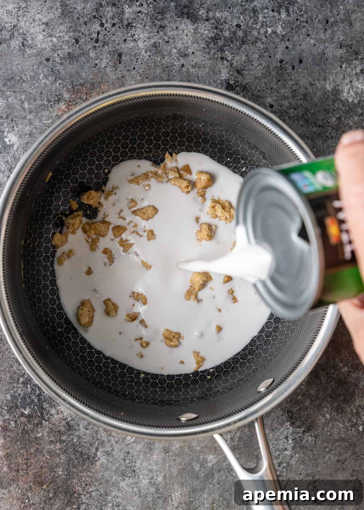 Overhead process shot: creamy coconut milk is added to the skillet with melted palm sugar and salt, creating the luscious sauce for Chak Ktiss.