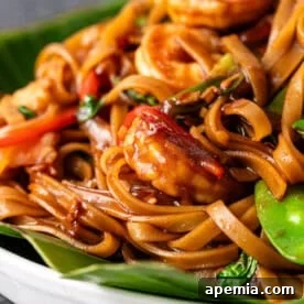 A top-down shot of a serving of Drunken Noodles (Pad Kee Mao) with shrimp, vibrant vegetables, and Thai basil, presented beautifully.