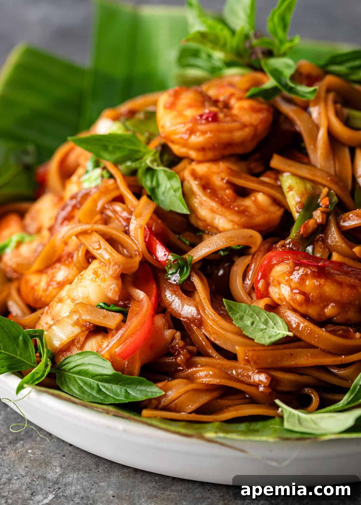 Bold and Spicy Thai Basil Noodles 3 Closeup shot of my homemade Drunken Noodles recipe, showcasing plump shrimp, vibrant vegetables, and aromatic Thai basil, drenched in the signature dark, savory sauce.