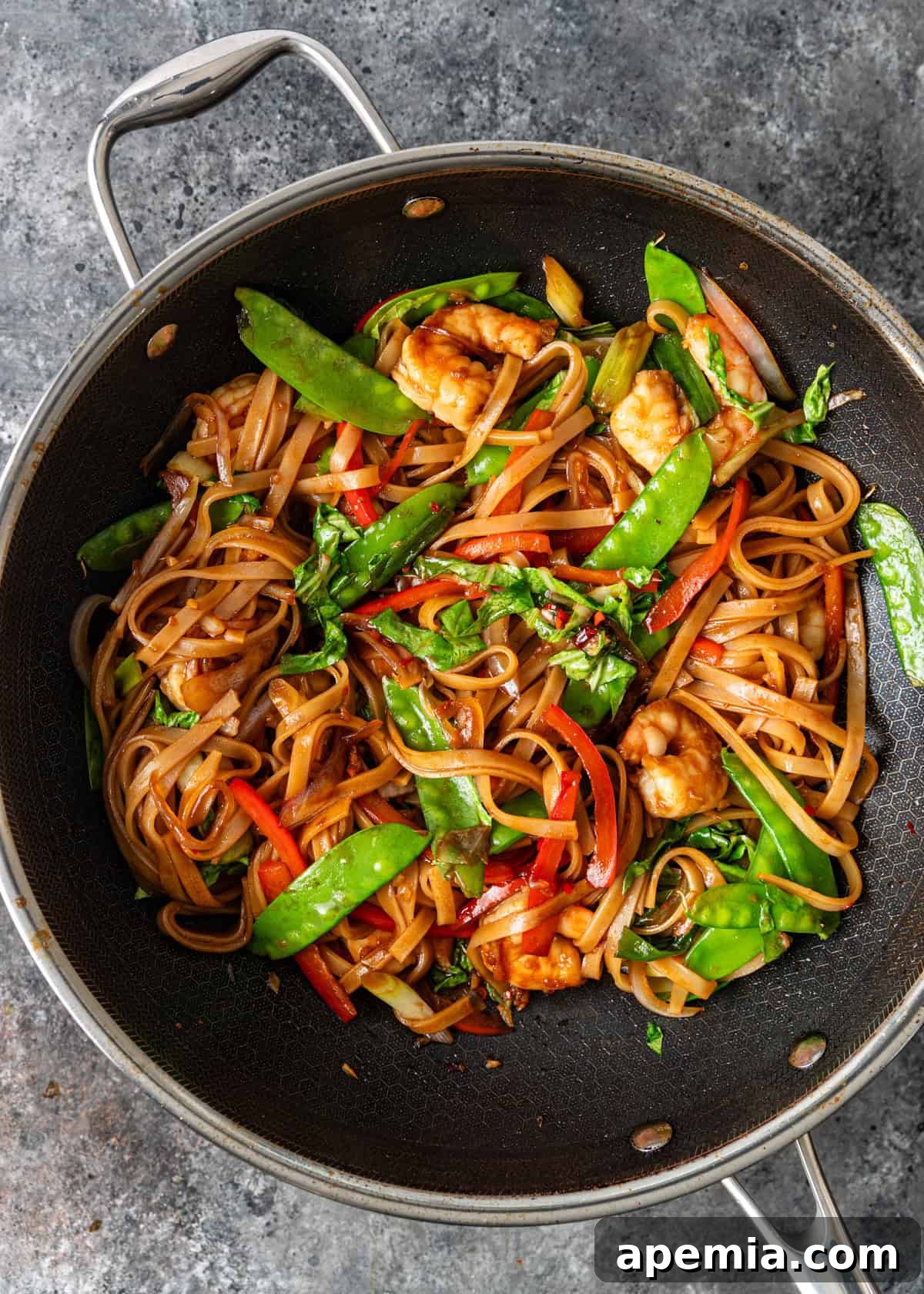 Bold and Spicy Thai Basil Noodles 7 Overhead process shot of Drunken Noodles being stir-fried in a traditional wok, showing the noodles, protein, and vegetables combining with the sauce.