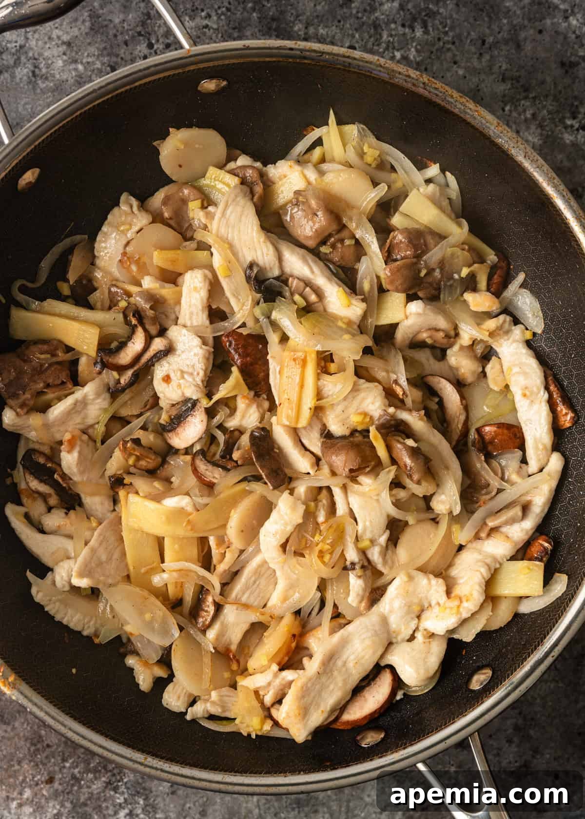 Process shot: The chicken and vegetables actively cooking together in a large wok, creating a vibrant mix of colors and textures as they meld their flavors.