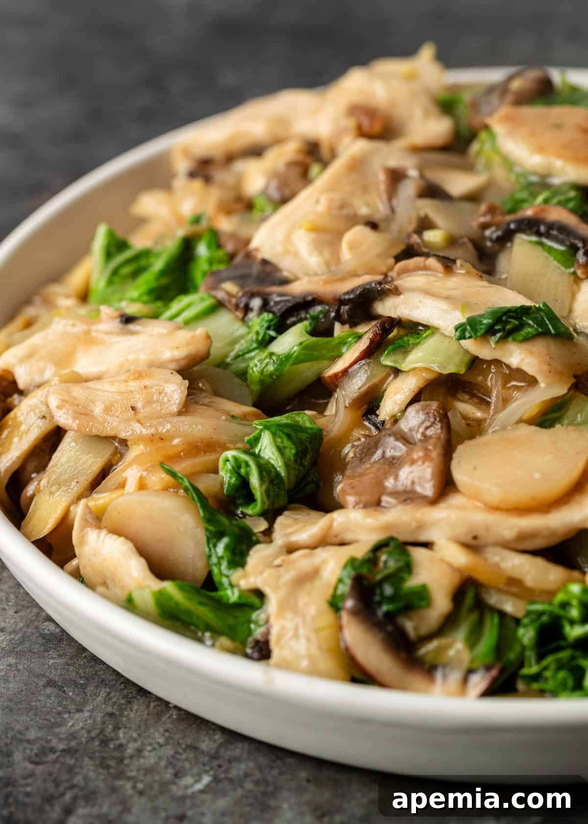 Close-up shot of the finished Moo Goo Gai Pan, focusing on the crisp water chestnuts and fresh bok choy amidst the perfectly cooked chicken and mushrooms, showcasing the dish's vibrant texture.