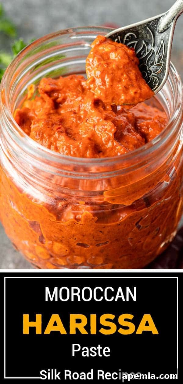 Close up of a spoonful of rich, red harissa paste, showcasing its smooth texture and vibrant color.