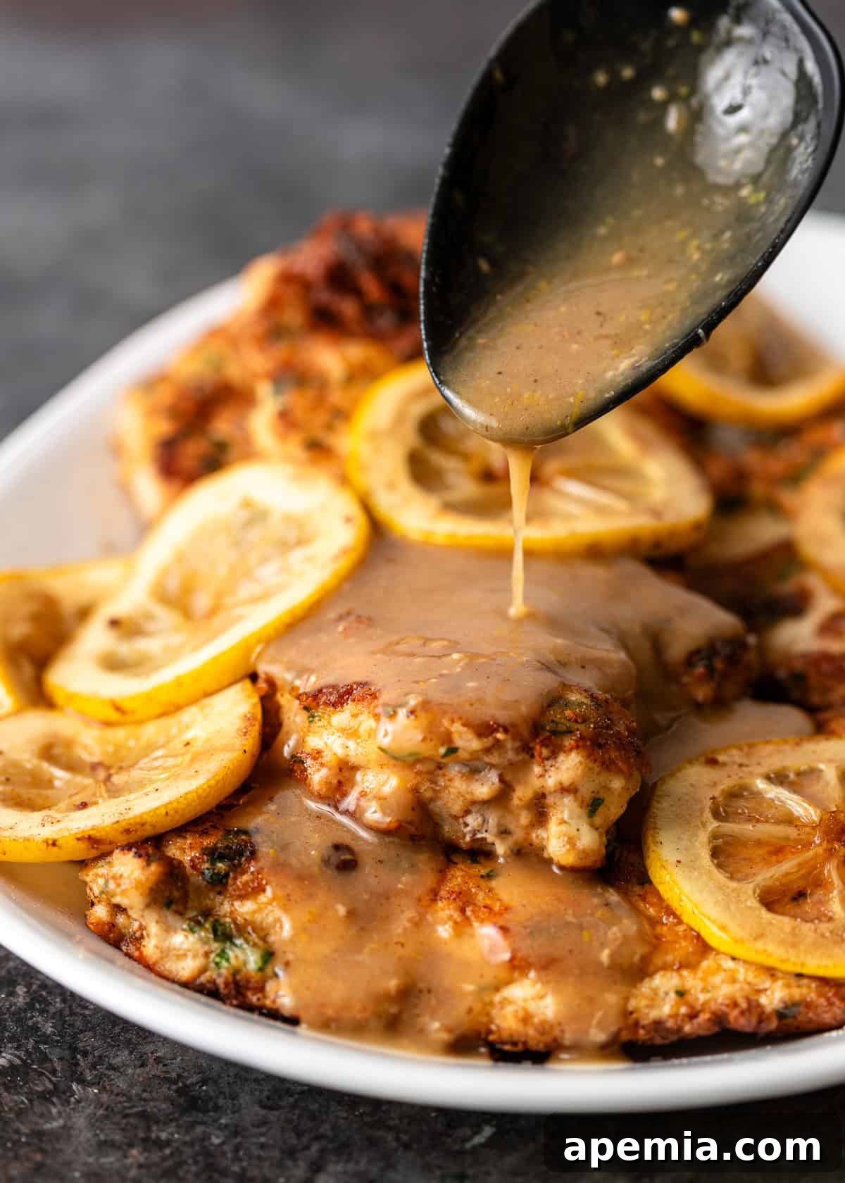 closeup: pouring sauce over a plate full of chicken francese