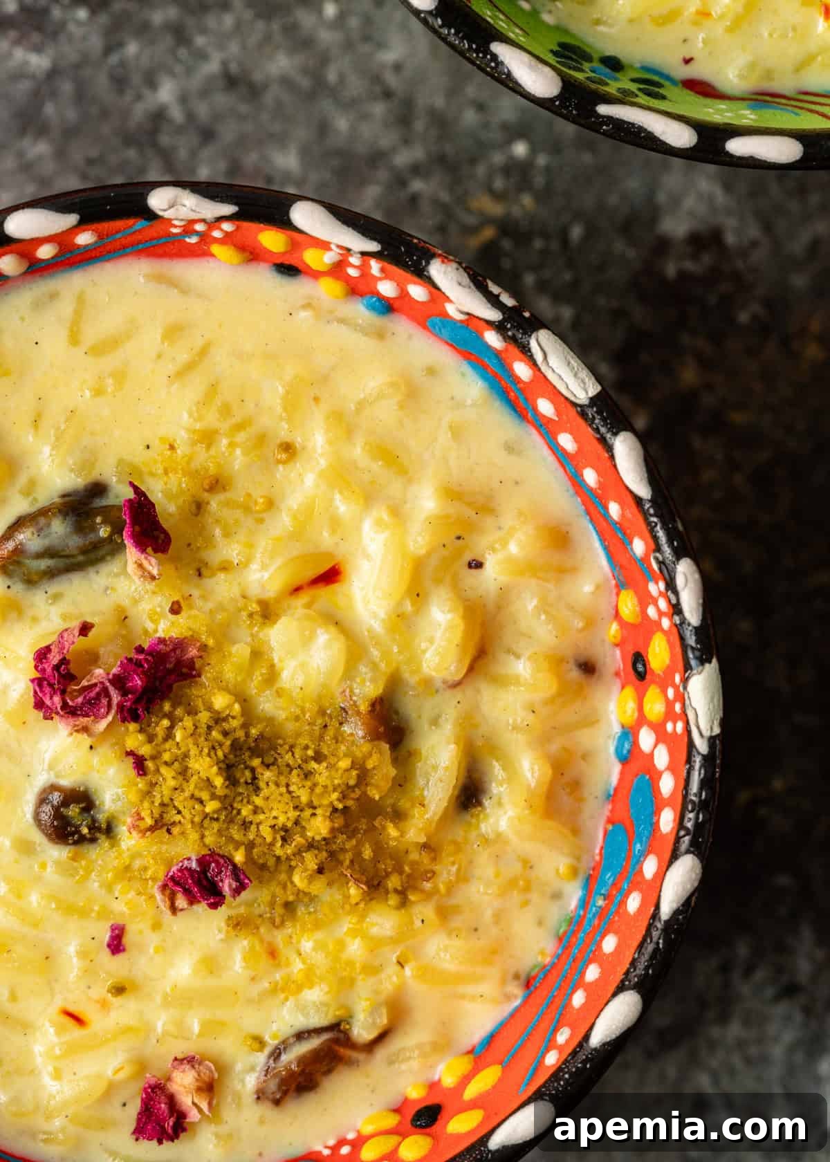 Indian Kheer Sweet Perfection 8 extreme closeup: a small bowl of kheer with flower petals and ground nuts on top