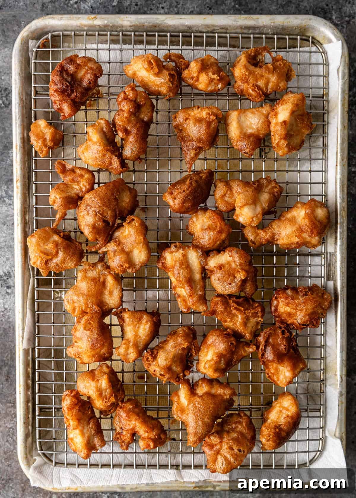 Overhead view of crispy fried almond chicken pieces cooling on a wire rack after being double-fried