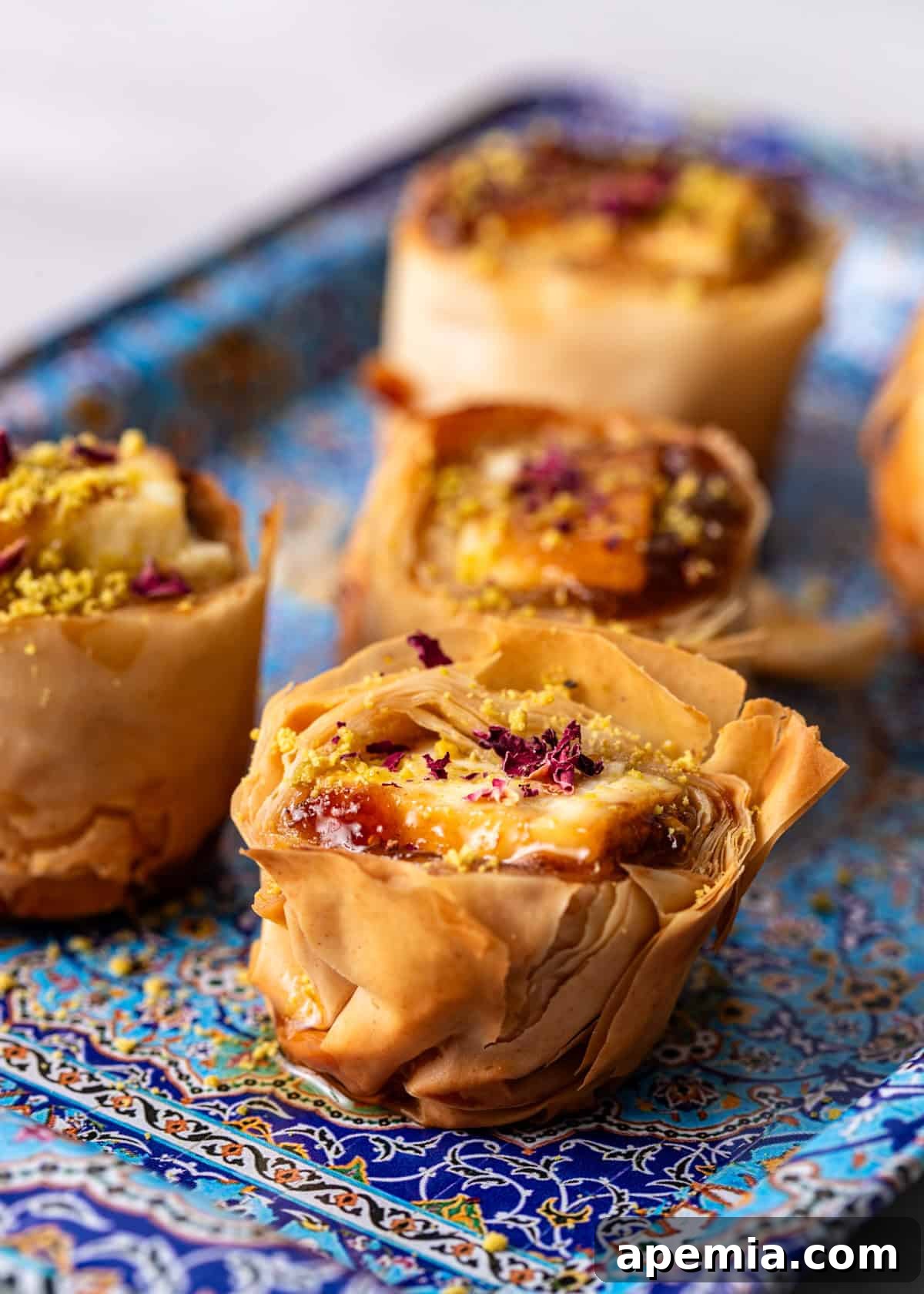 Closeup shot of crispy, golden-brown baked feta in filo, elegantly topped with delicate rose petals, ready to be served.