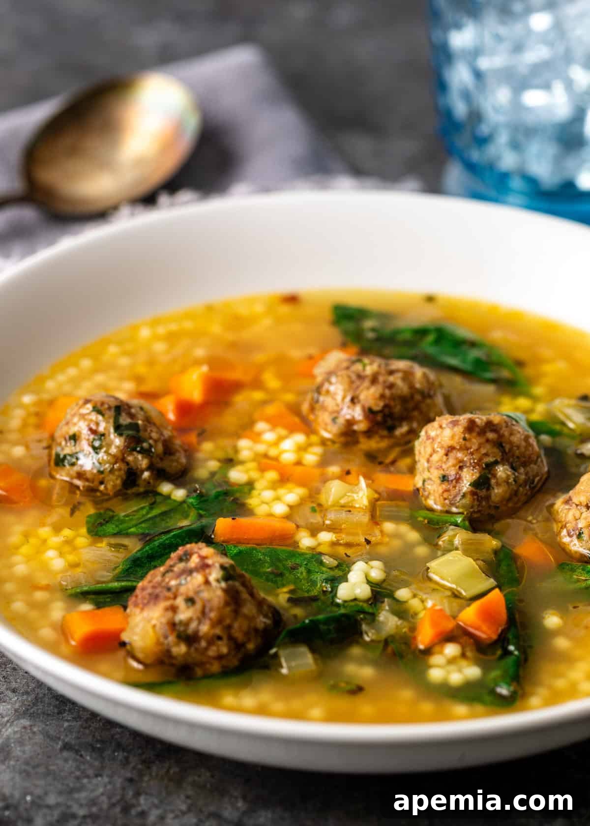 closeup: a bowl of Italian wedding soup with meatballs, spinach, carrots, and celery