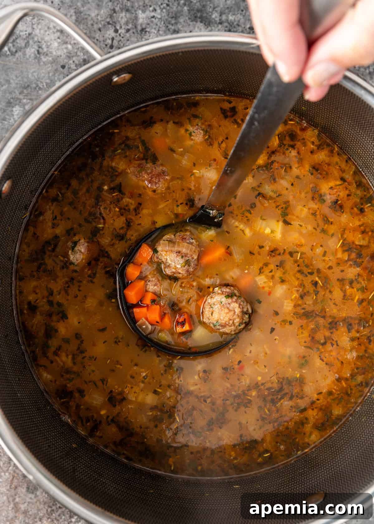 overhead: Italian wedding soup in a large pot with a ladle