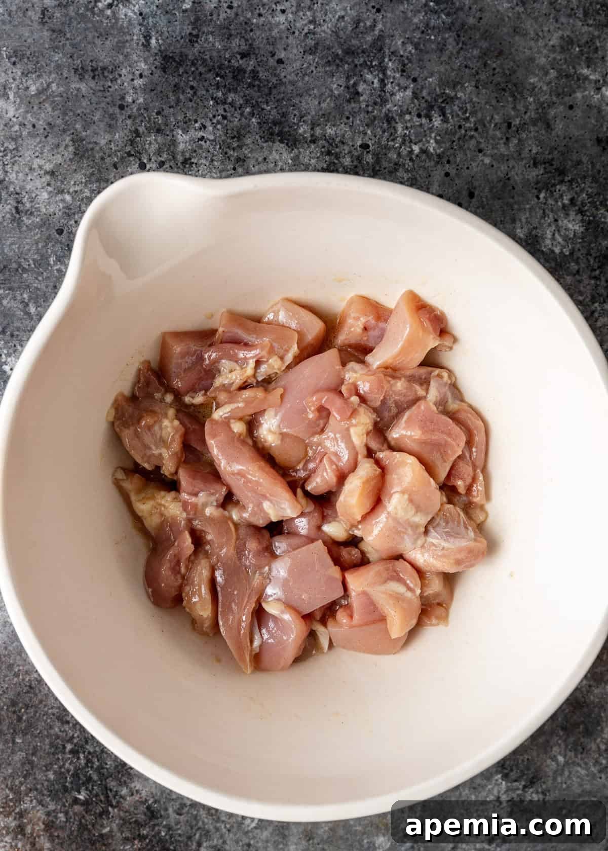 Overhead process shot: chicken pieces marinating in a bowl with liquids, soaking up the flavors for General Tso's chicken.