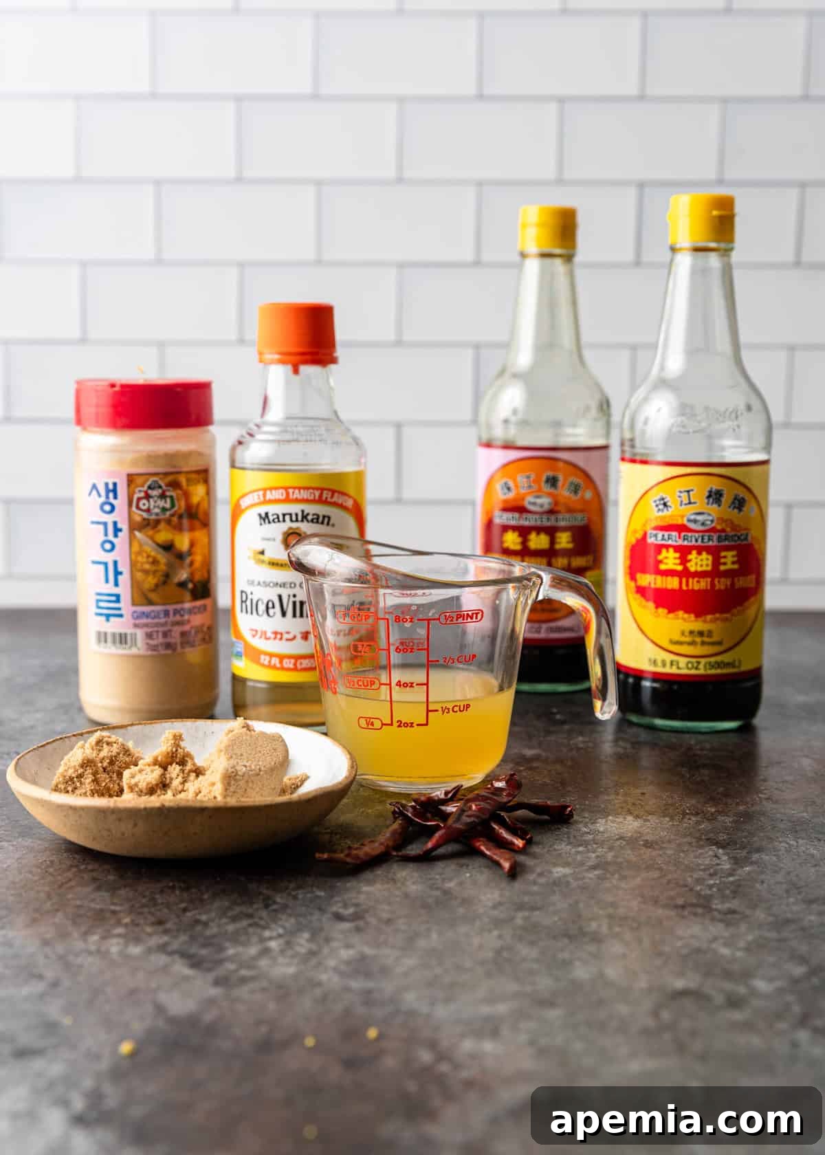 Process shot: various sauce ingredients for General Tso's chicken, including soy sauce, brown sugar, and spices, measured out and ready to be combined.
