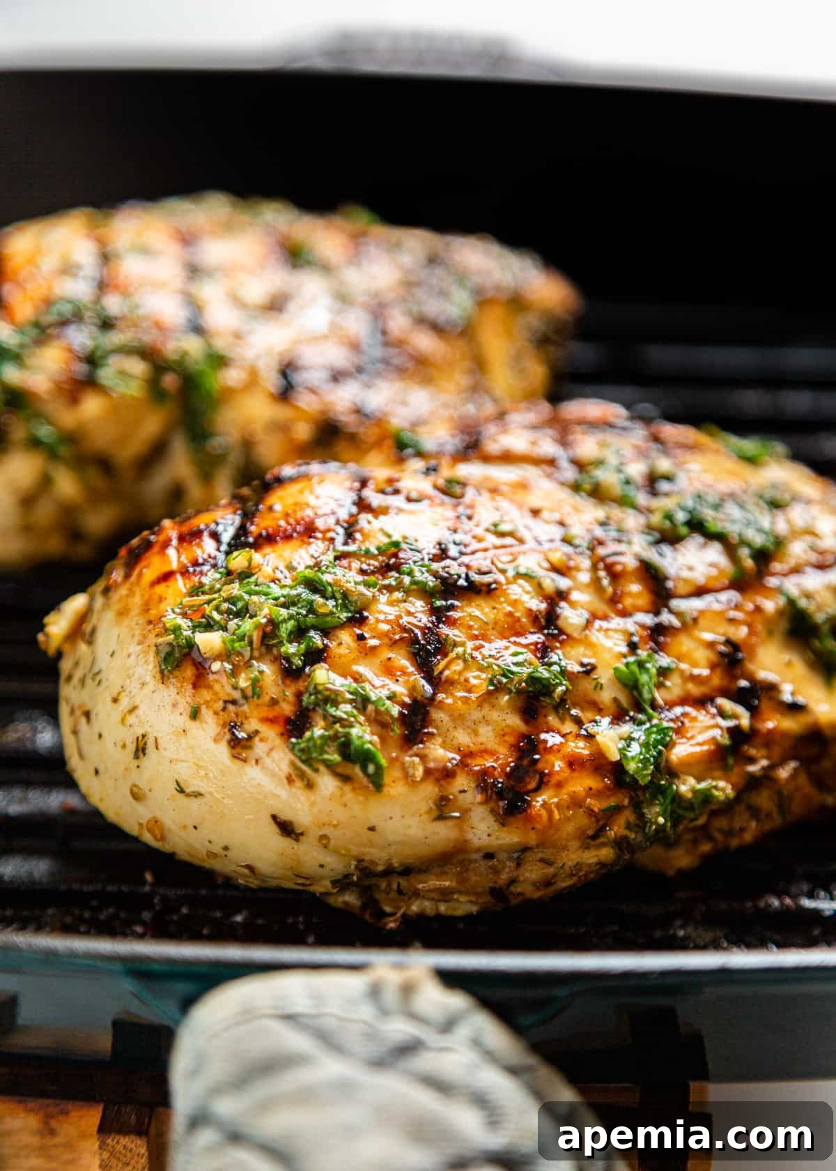 Closeup shot of marinated Greek chicken sizzling on a hot grill, showing perfect sear marks.