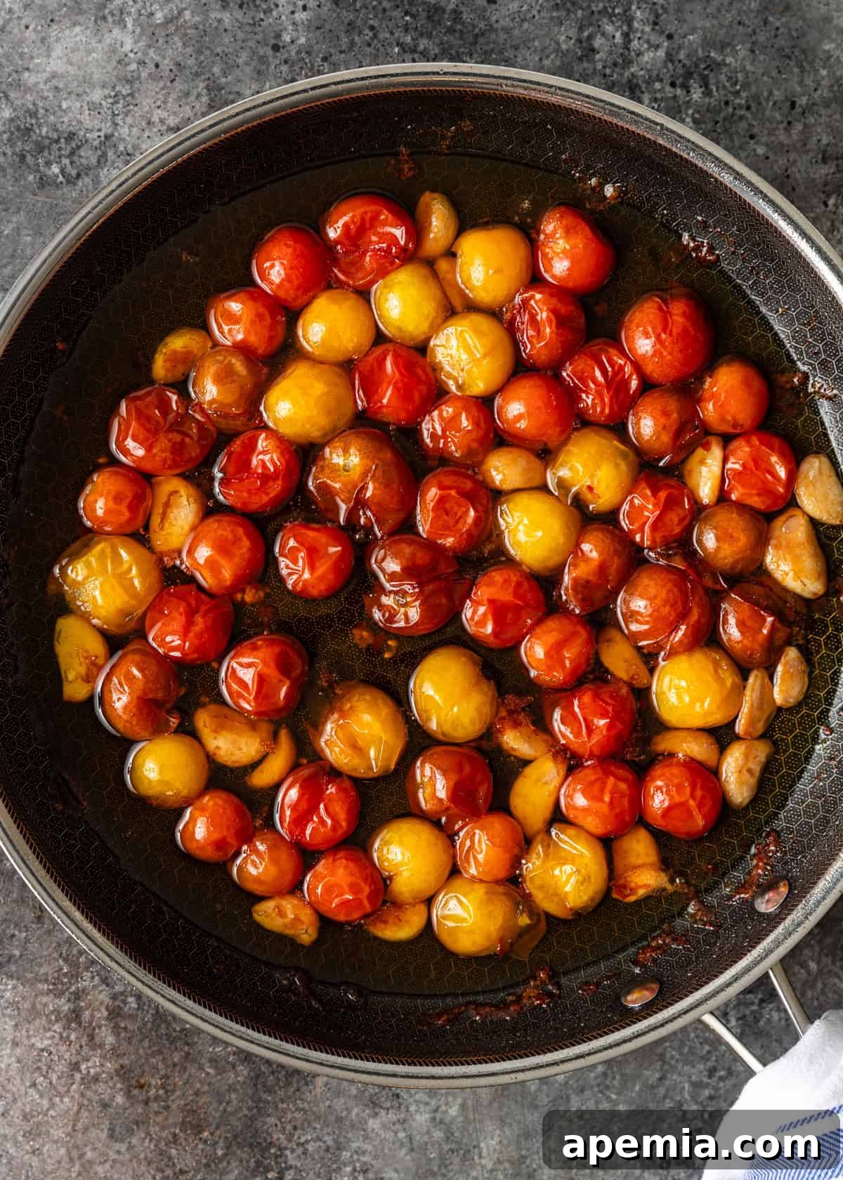 Overhead shot: stovetop tomato confit after 1 hour of gentle cooking, showing tender tomatoes and softened garlic.