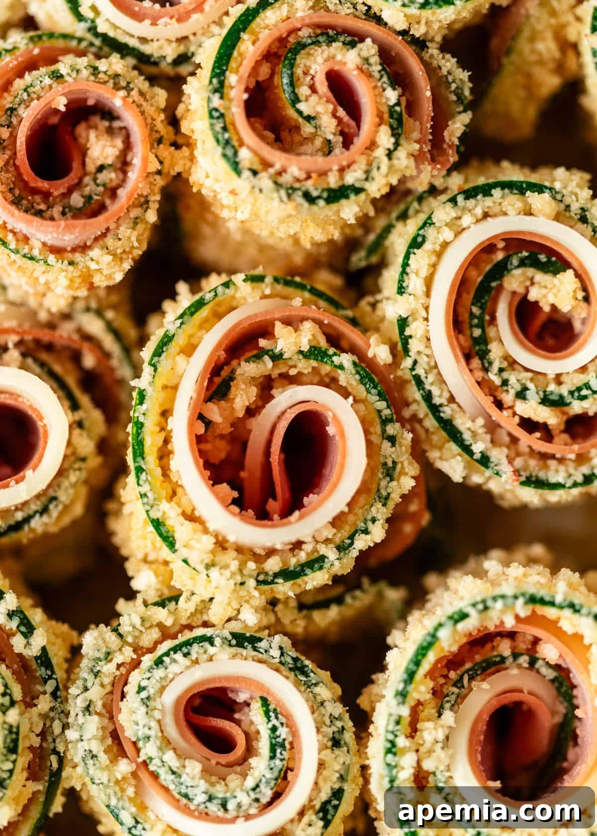 Extreme closeup of uncooked zucchini rolls neatly arranged before baking, showcasing the fillings.