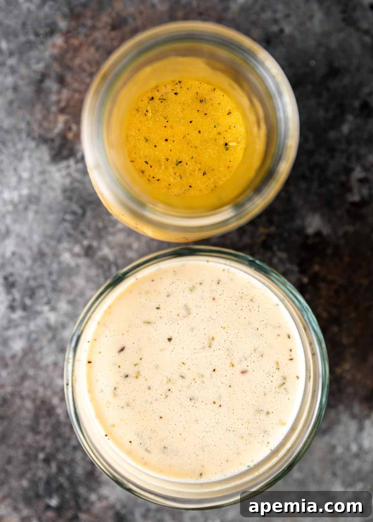 Homemade Italian Dressings Two Ways 3 Two clear glass jars filled with homemade Italian dressing, showcasing its rich texture and inviting color.