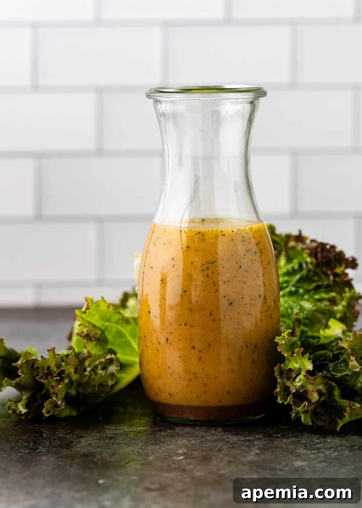 Homemade Italian Dressings Two Ways 10 Side view of Italian dressing in a glass jar, elegantly placed with crisp lettuce leaves around its base.