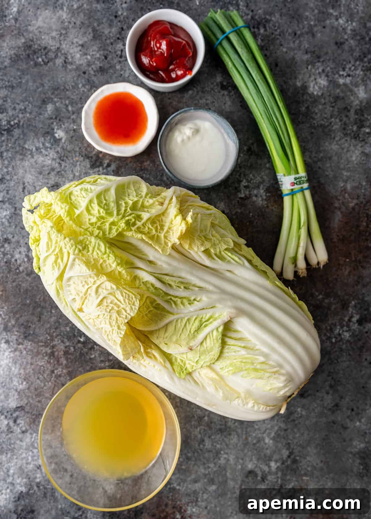 Overhead shot showcasing all the fresh ingredients meticulously laid out, ready for making the cabbage stir fry recipe, including whole Napa cabbage, green onions, and garlic.