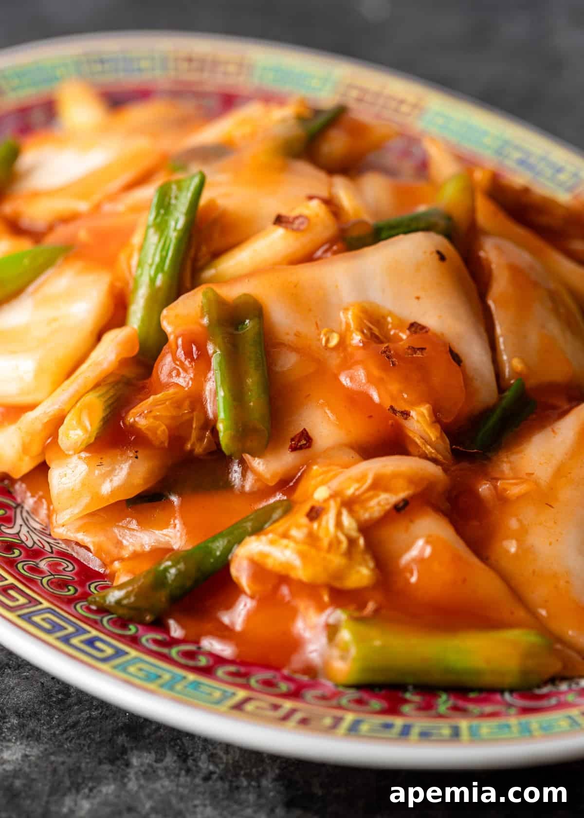 Another close-up shot of the hot and sour cabbage stir fry, highlighting the texture and glistening sauce, with green onions and red pepper flakes clearly visible.