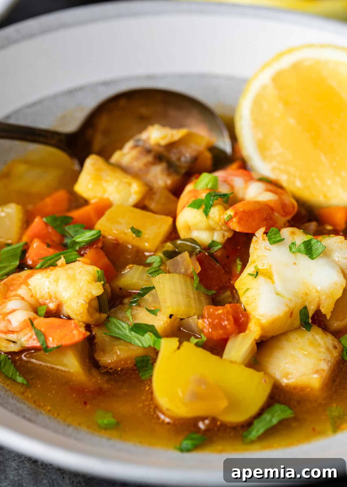 Hearty Greek Fish Stew 14 Close-up shot of a serving of Greek fish soup in a bowl, featuring potatoes, fish, shrimp, and celery, ready to eat.