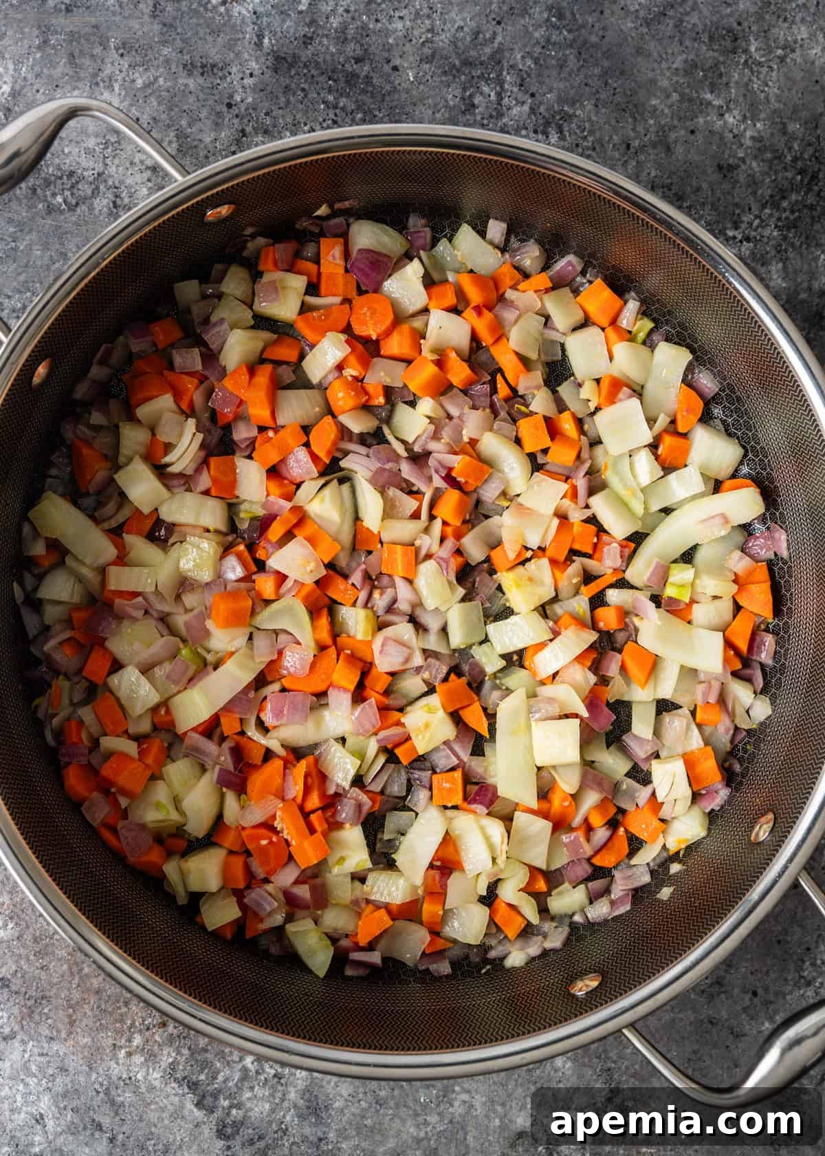 Hearty Greek Fish Stew 7 Overhead process shot showing carrots, onions, and fennel simmering in a soup pot, forming the aromatic base of the stew.