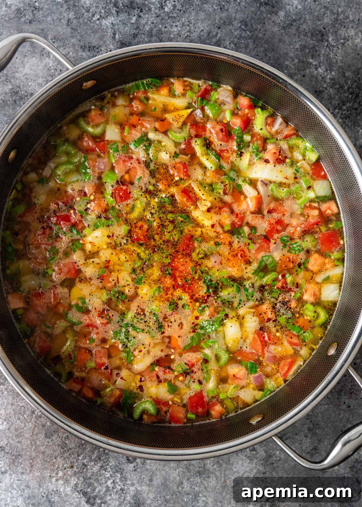 Hearty Greek Fish Stew 9 Overhead process shot of a soup pot filled with vegetables, broth, and vibrant saffron threads, simmering to perfection.