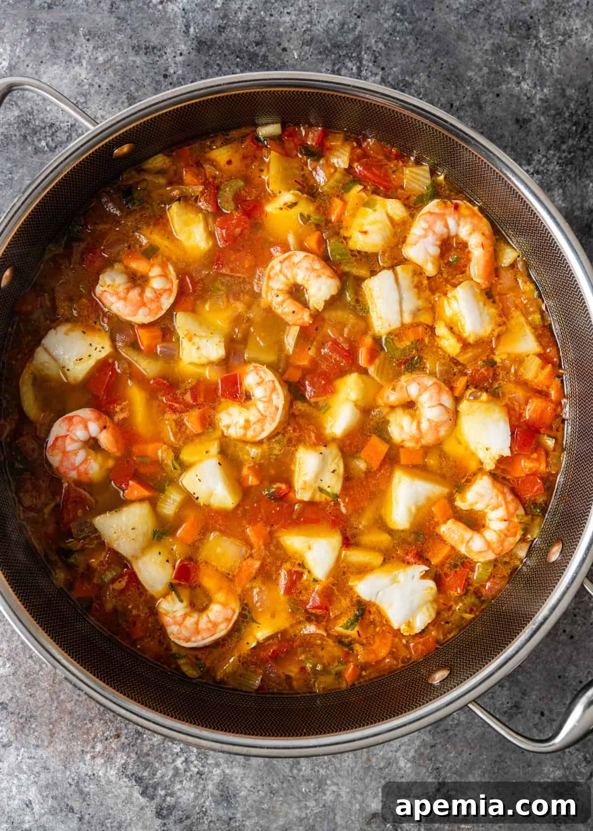 Hearty Greek Fish Stew 10 Overhead process shot displaying the fish stew with white fish and shrimp gently simmering in the pot, completing the dish.