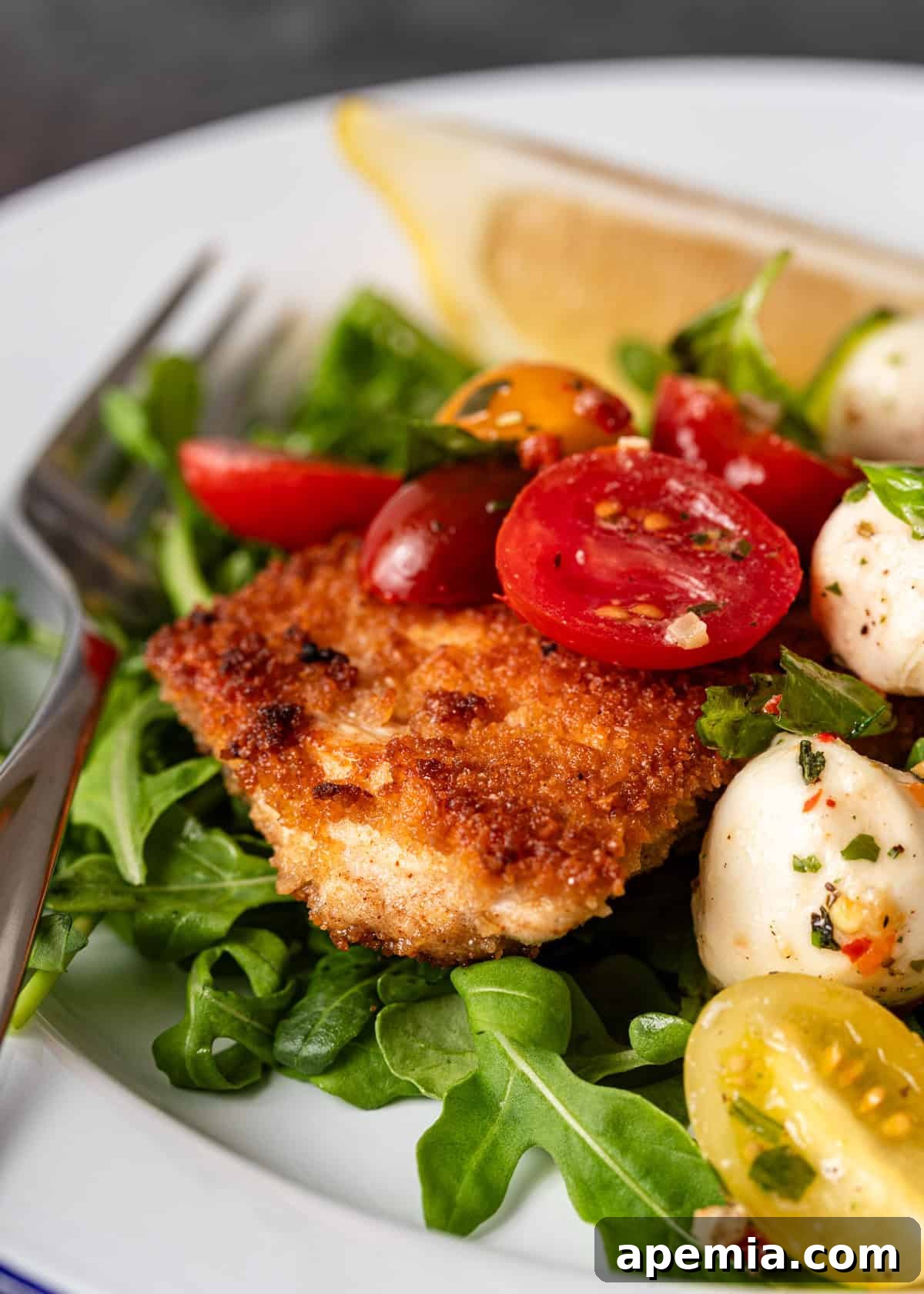 A tantalizing close-up of crispy chicken Milanese, adorned with fresh mozzarella, vibrant basil, and juicy tomatoes, showcasing the perfect blend of textures and colors.