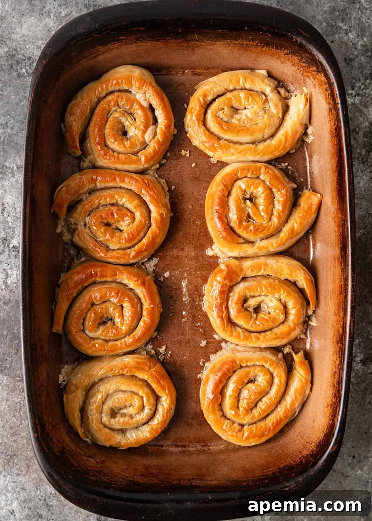 Mhencha: Moroccan Coiled Almond Delight 12 Overhead shot of a baking dish filled with perfectly baked, golden-brown Mhencha pastries, fresh out of the oven.