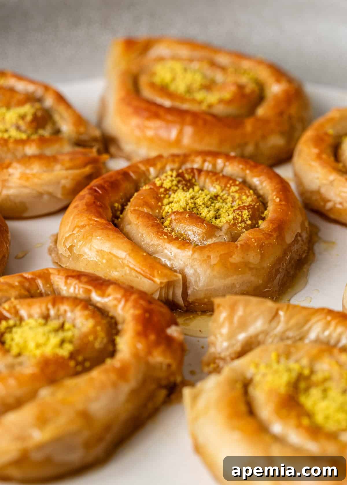 Mhencha: Moroccan Coiled Almond Delight 15 Closeup of the Mhencha recipe on a serving platter, showing a piece with melted butter and honey drizzling over it.