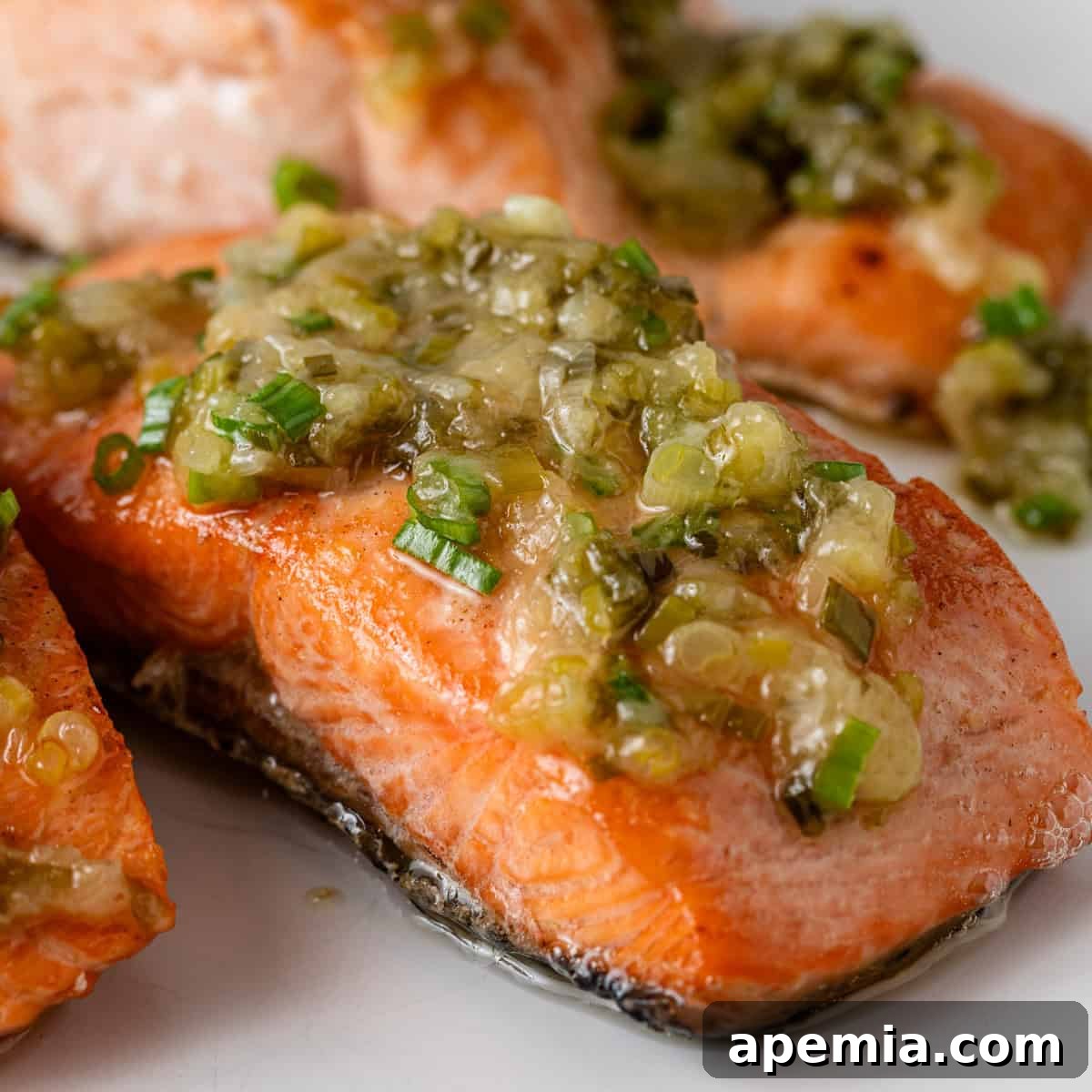 Closeup of crispy baked salmon topped with a generous amount of homemade ginger scallion sauce