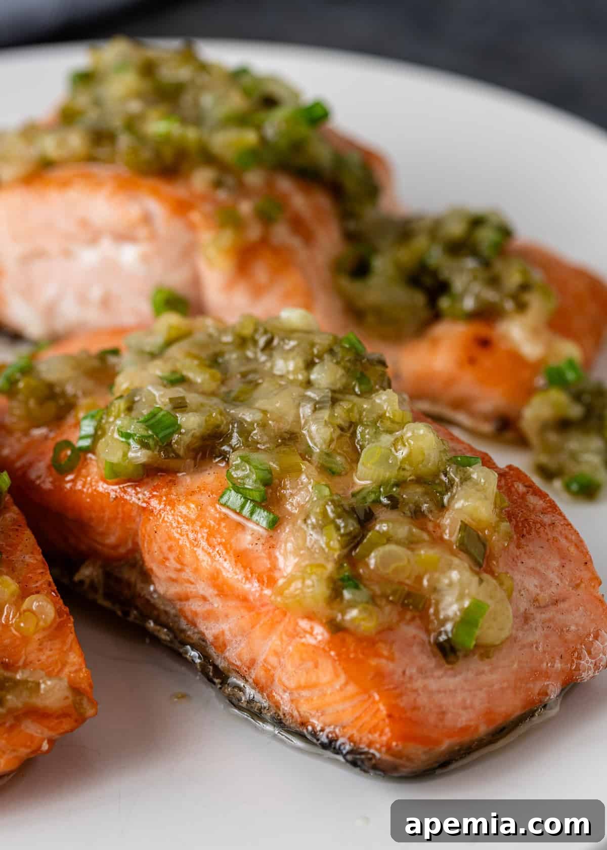 Closeup of a single serving of my ginger scallion sauce recipe layered over a baked salmon fillet