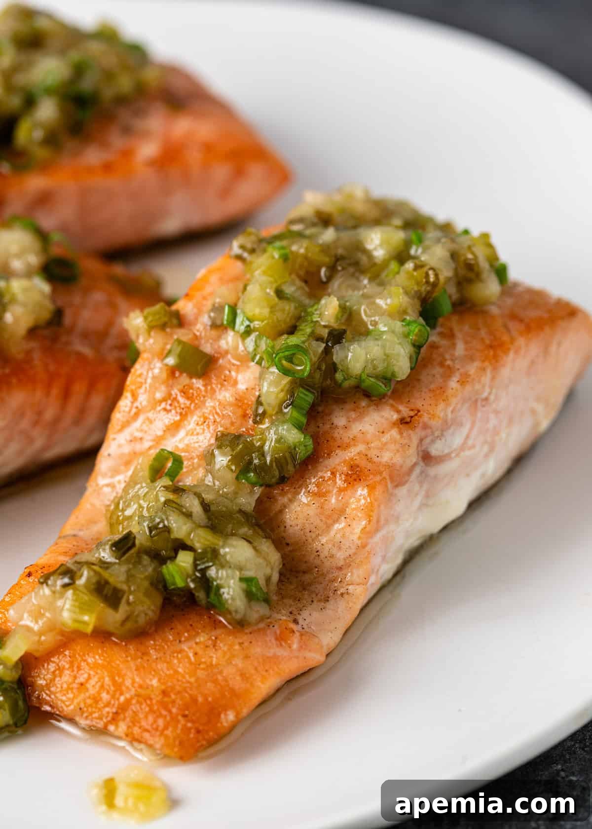 Closer view of a baked salmon fillet generously adorned with my homemade ginger scallion sauce