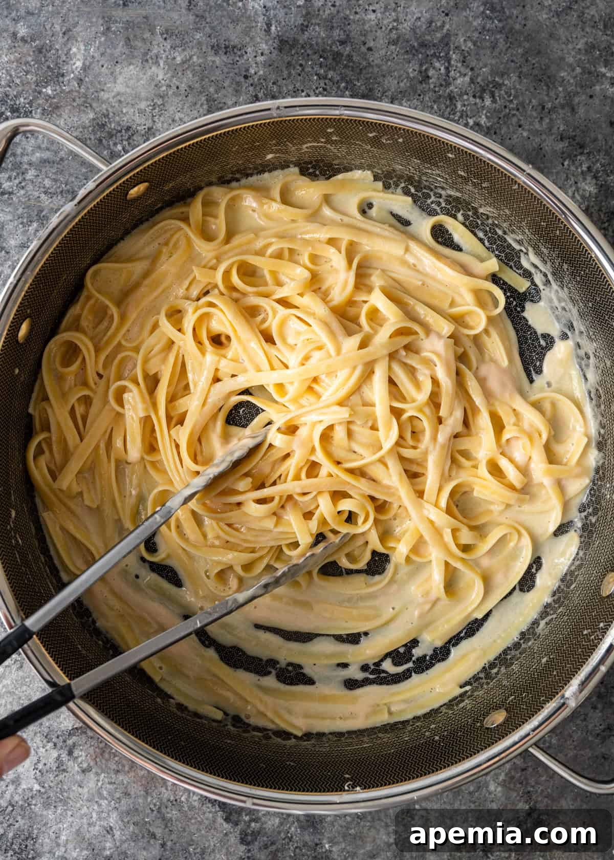 overhead process shot: mixing and tossing the alfredo pasta recipe to emulsify