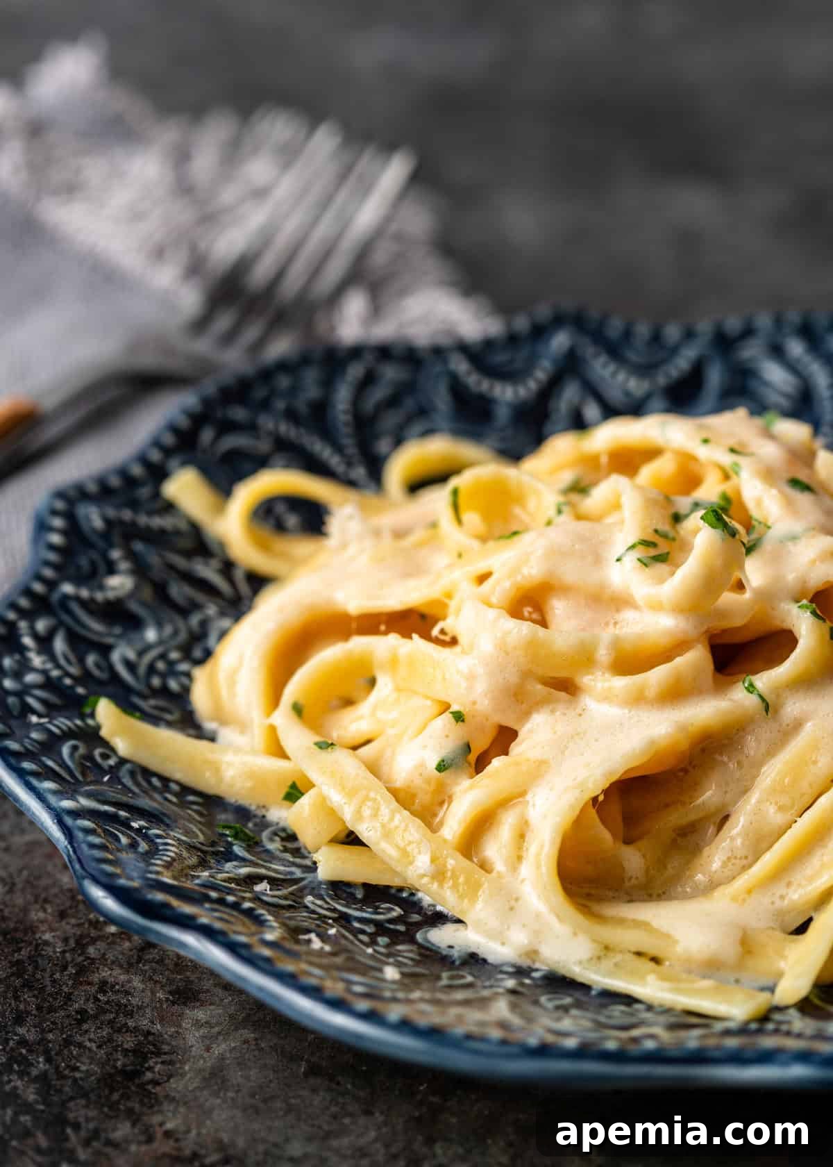 side view closeup: a serving of my fettuccine alfredo recipe on a dark blue plate