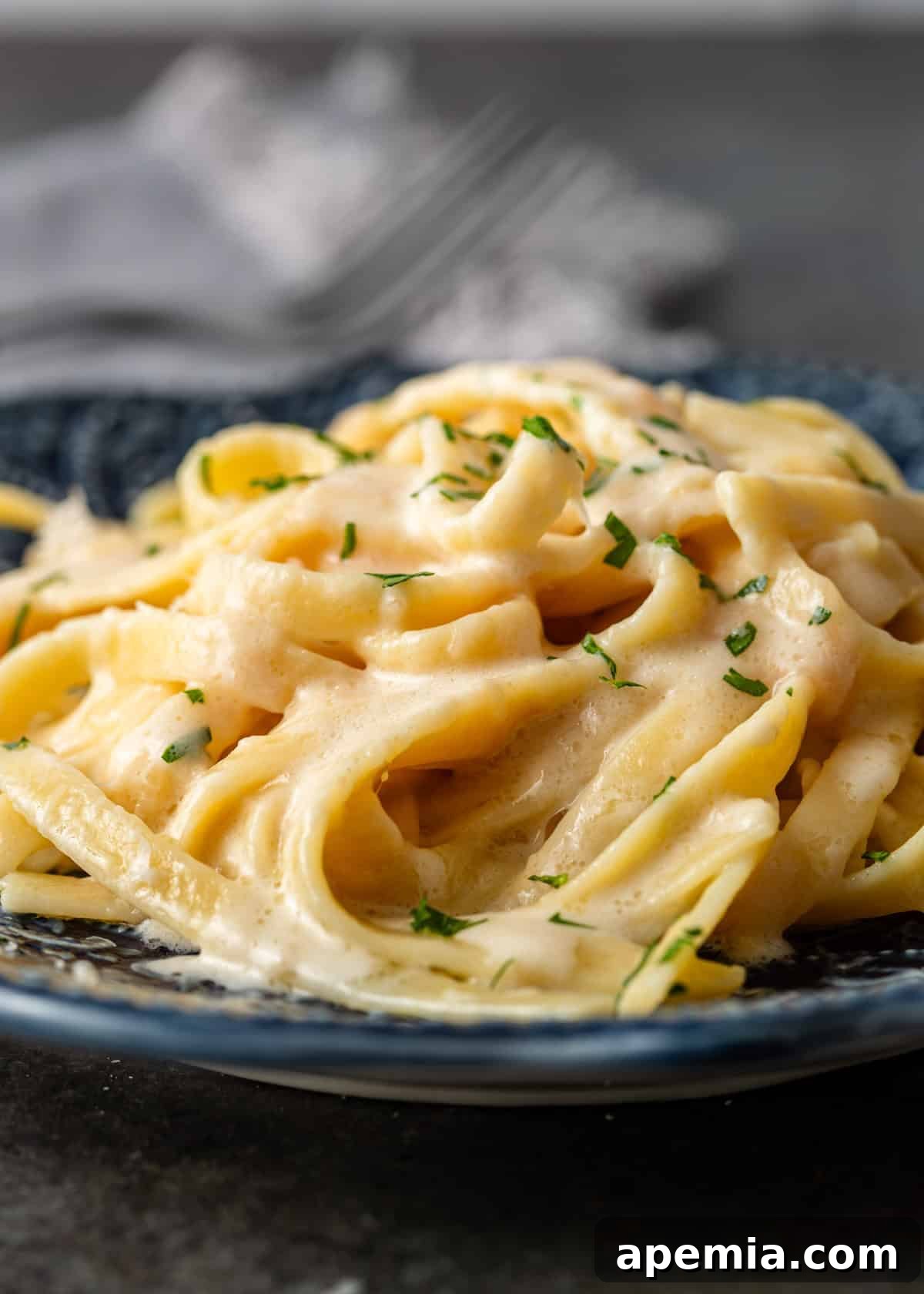 side view closeup: a serving of my alfredo pasta recipe with fresh herbs on top