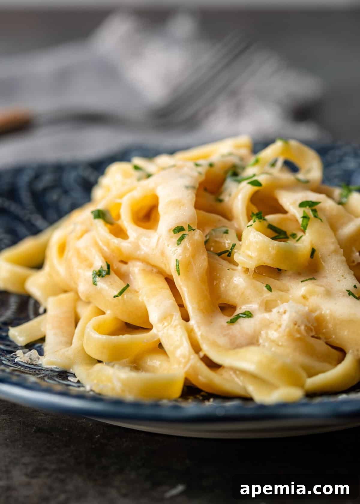closeup side view: a serving of fettuccine al burro on a blue plate