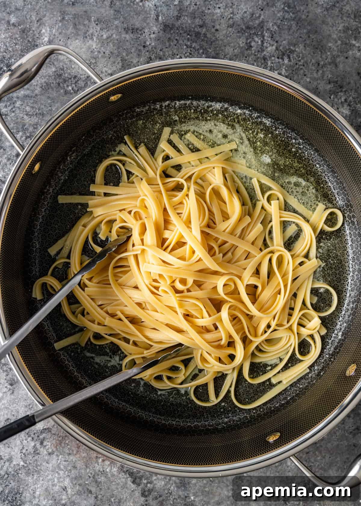 overhead process shot: adding pasta to the skillet directly after it's done cooking