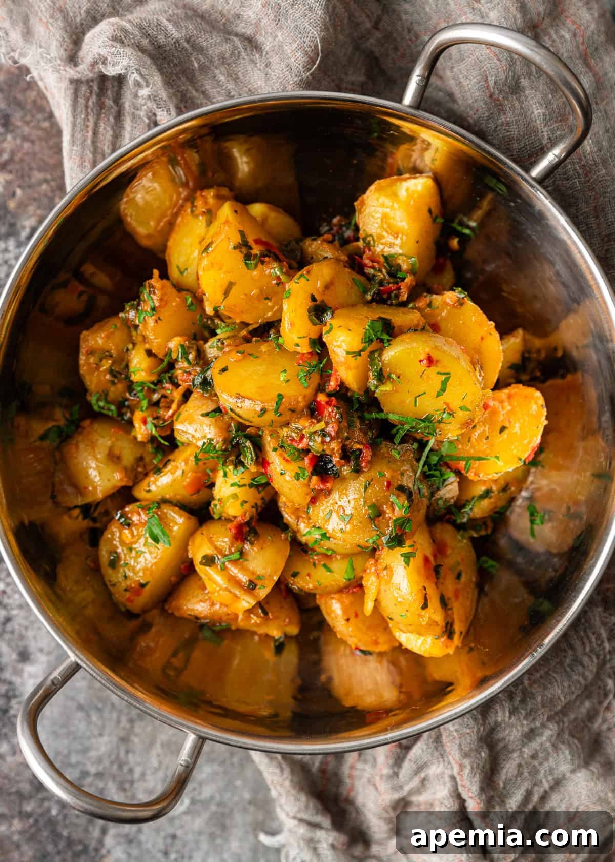 Overhead view of potatoes and peppers cooked in herb chili butter, served in a rustic metal bowl, highlighting their vibrant colors and enticing texture.