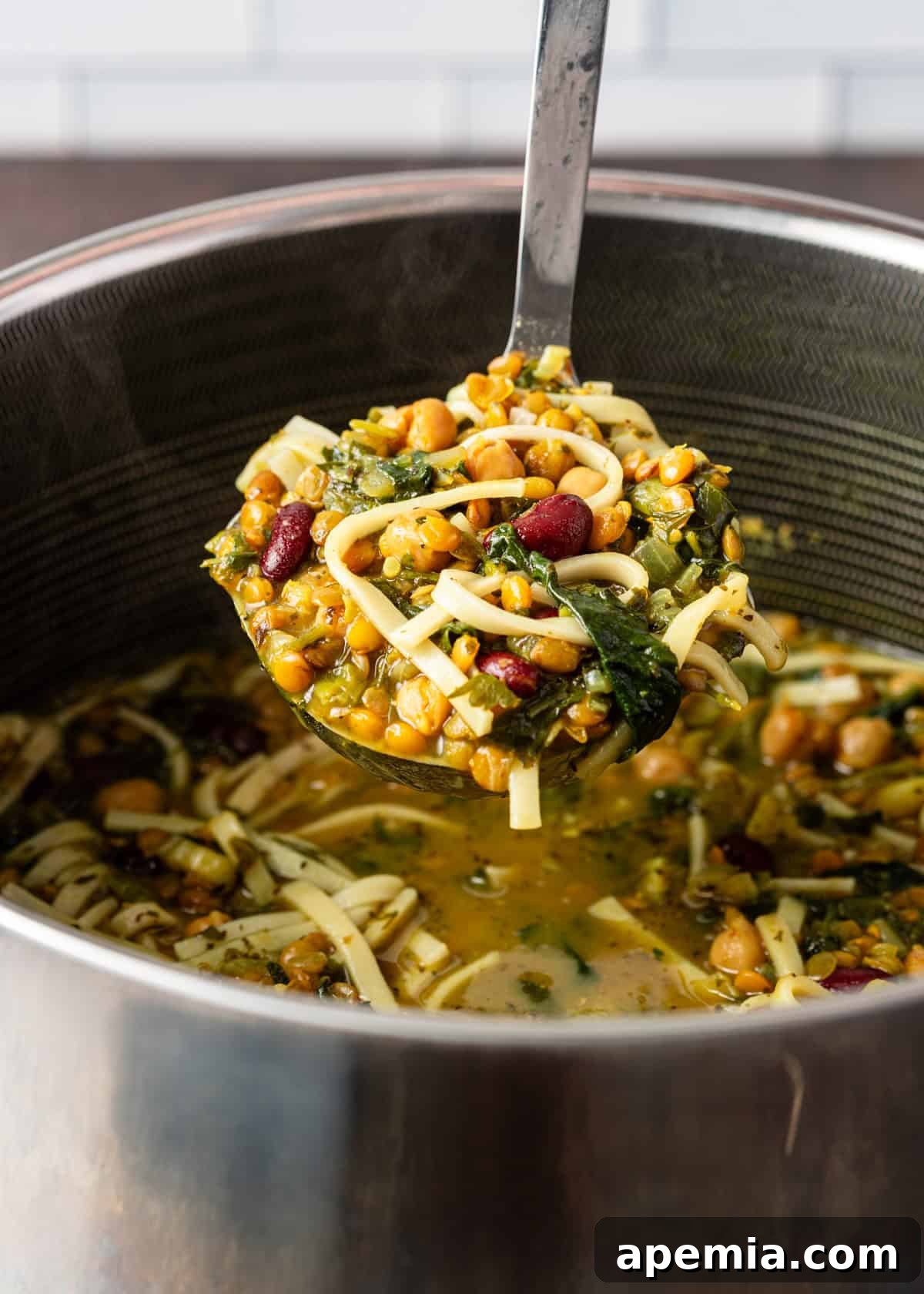 Closeup of a ladle full of homemade Ash Reshteh, showing the rich texture and ingredients.