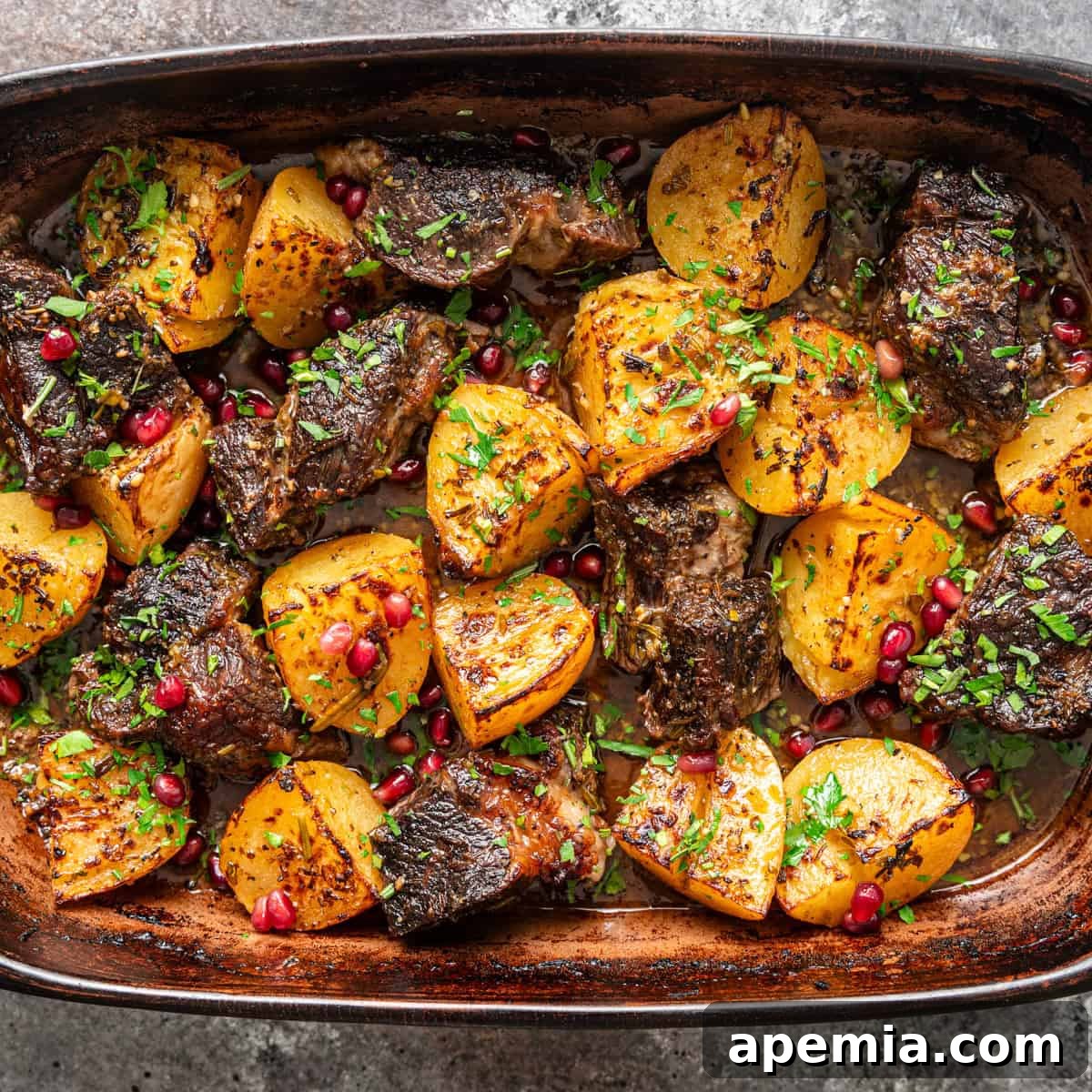 overhead: pot roast and potatoes with pomegranate and herbs on a baking dish