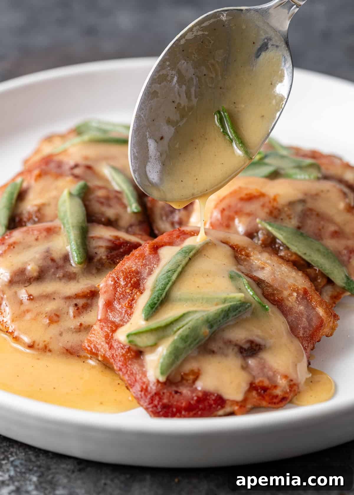 Side view: More of the delectable sage butter sauce being generously spooned onto a serving of saltimbocca.