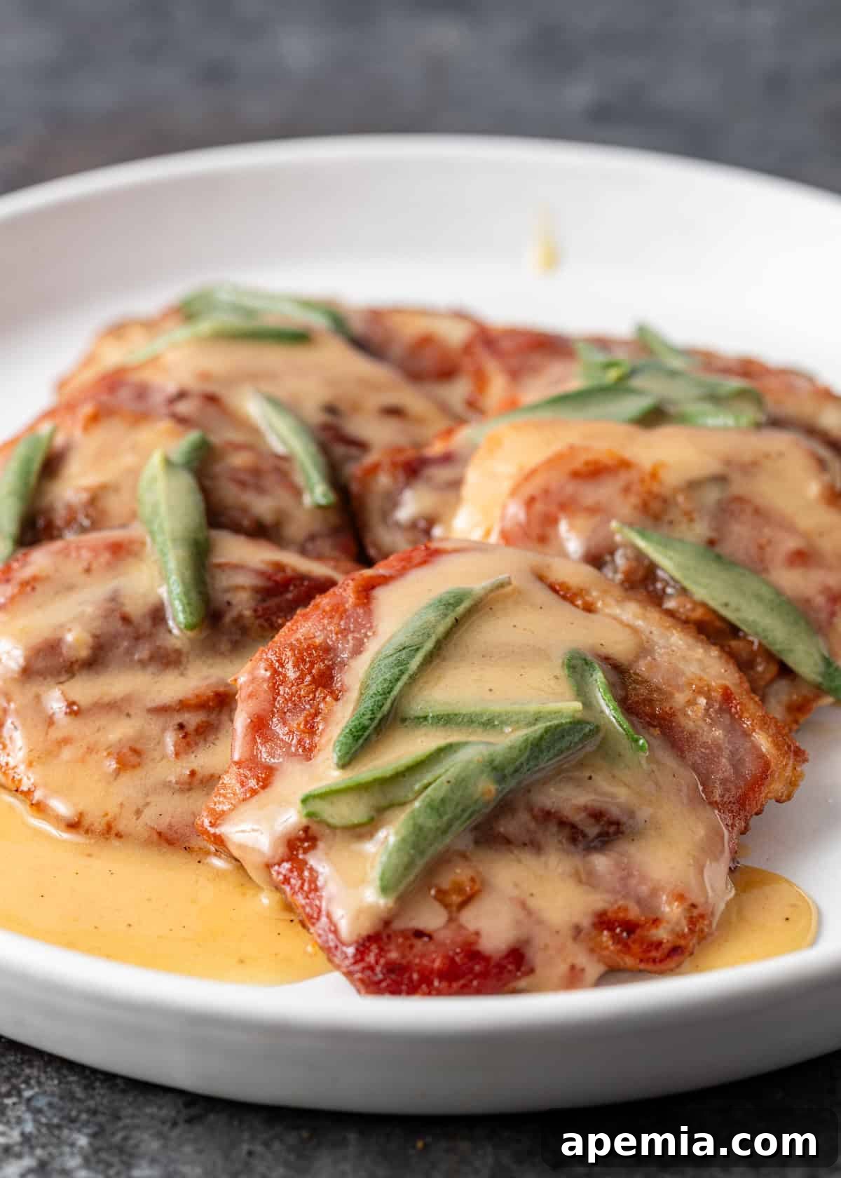 Side view: A fully assembled plate of Saltimbocca alla Romana, showing the layers of meat, prosciutto, and sage, glistening with sauce.