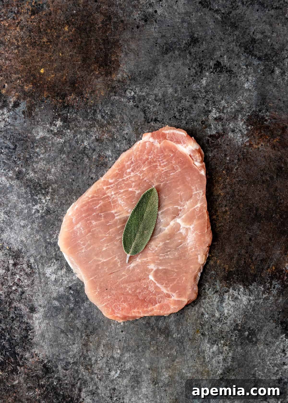 Process shot: Gently pressing a fresh sage leaf onto the pounded cutlet.