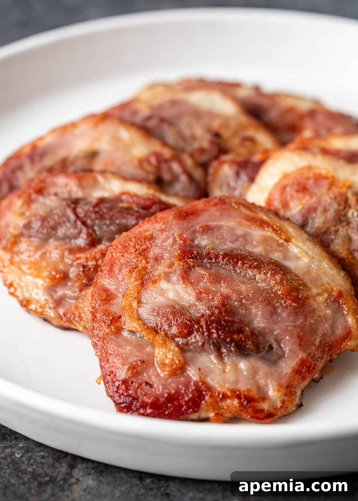 Closeup of a freshly fried pork saltimbocca cutlet, golden brown and ready for sauce, resting on a white plate.