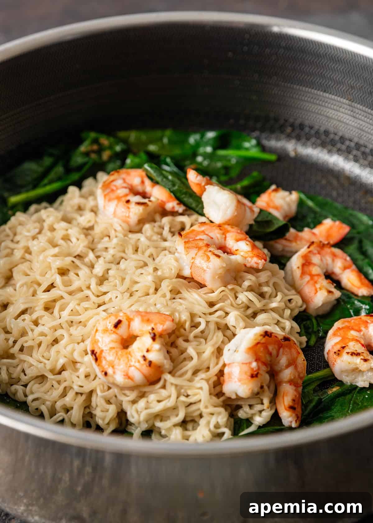 Zesty Gochujang Sesame Noodles 5 process shot: noodles, shrimp, and spinach in a skillet