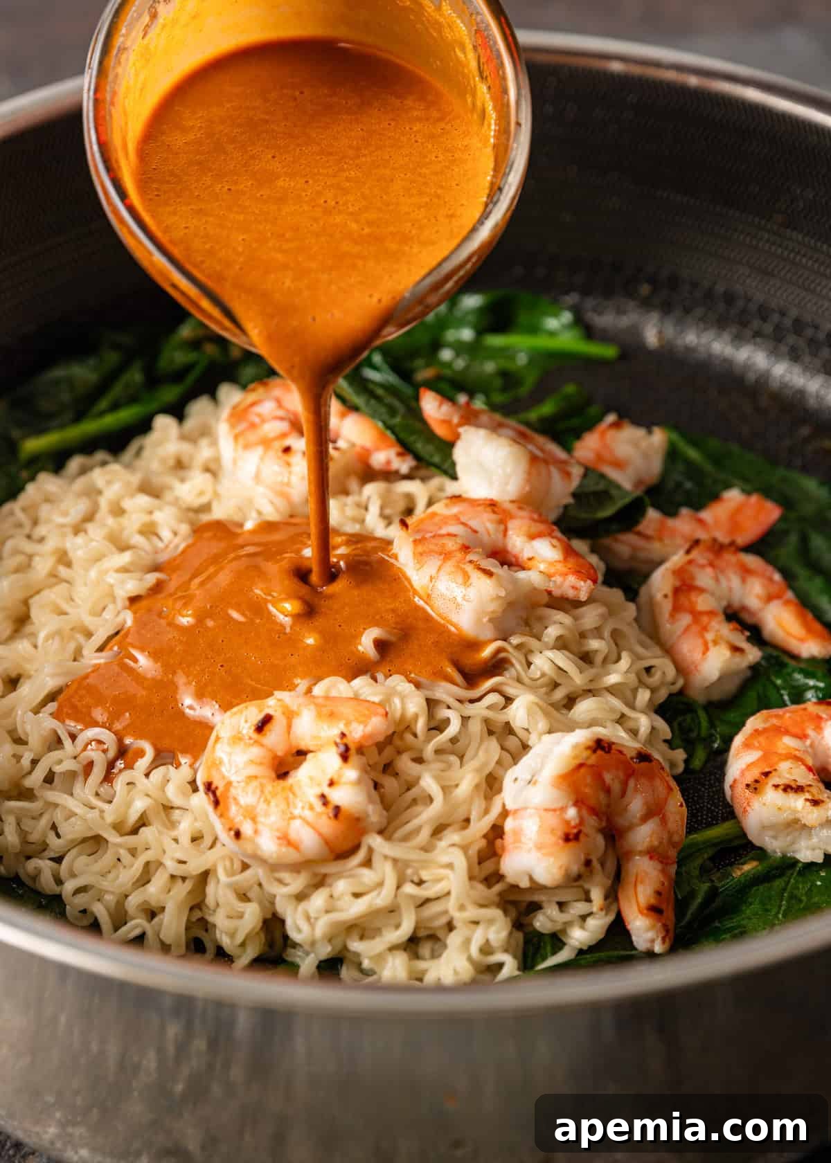 Zesty Gochujang Sesame Noodles 6 process shot: pouring gochujang noodles sauce over ingredients in the skillet