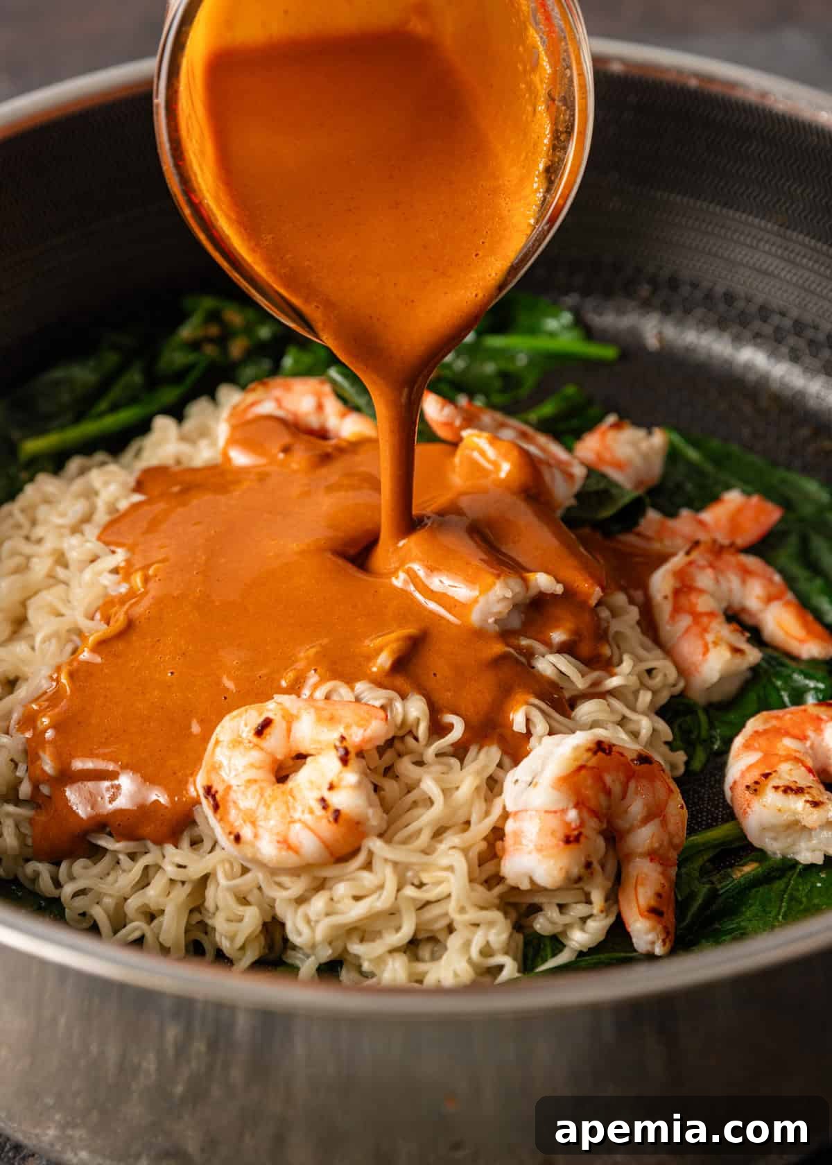 Zesty Gochujang Sesame Noodles 7 process shot: pouring sauce over my gochujang noodles recipe in a skillet