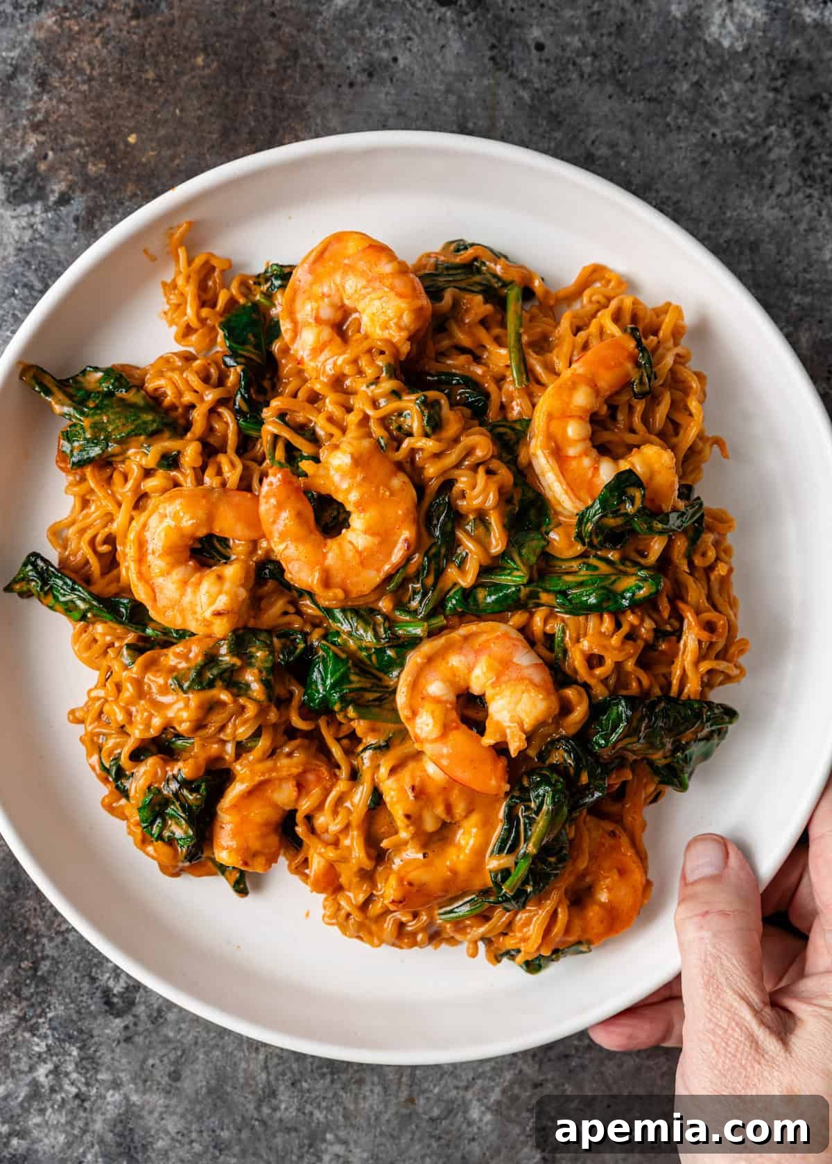 Zesty Gochujang Sesame Noodles 10 overhead: a hand holding a plate with a serving of my gochujang noodles recipe