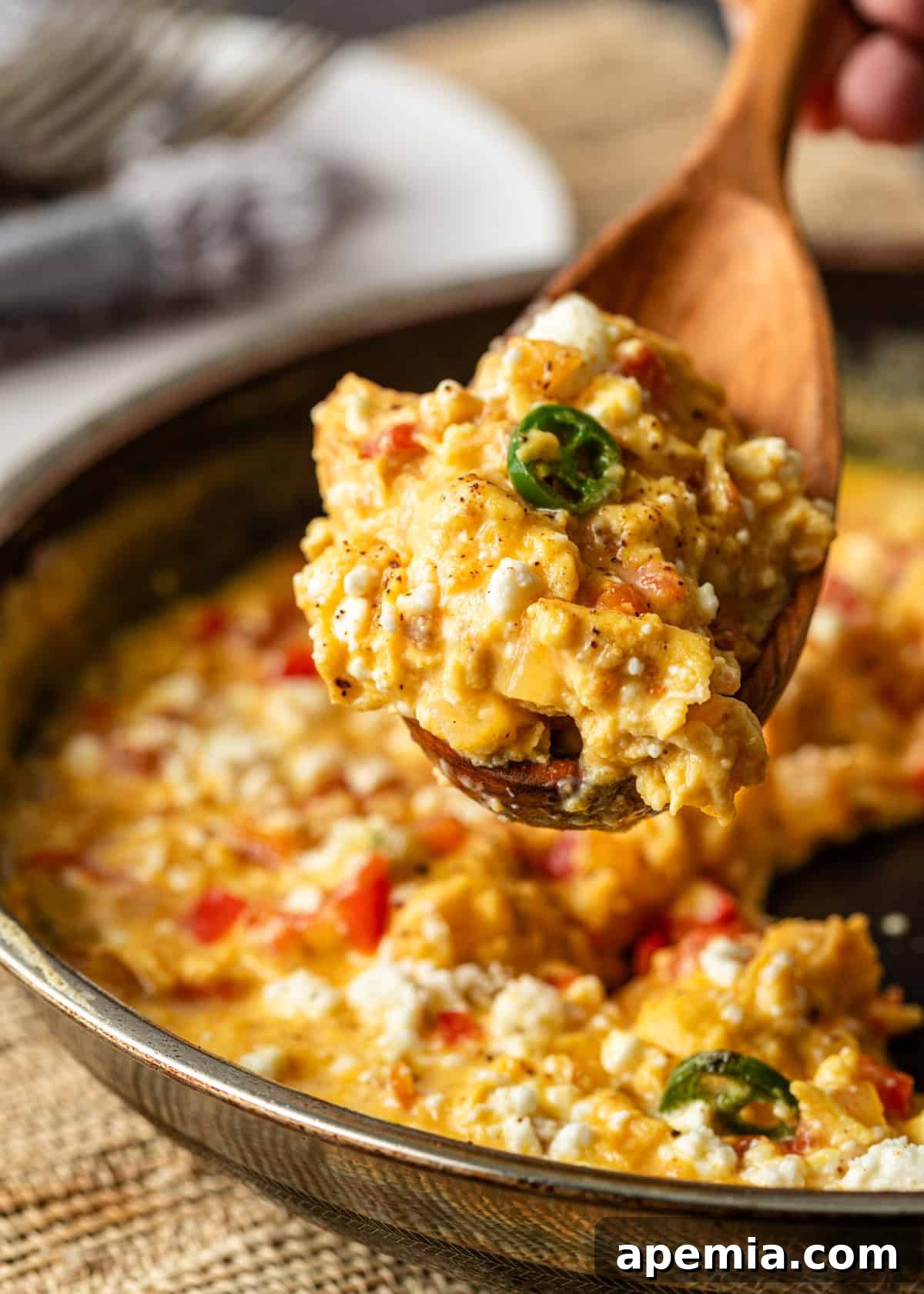 Menemen Classic Turkish Breakfast Scramble 8 Closeup of a wooden spoon serving a portion of Turkish scrambled eggs (menemen) from a skillet.